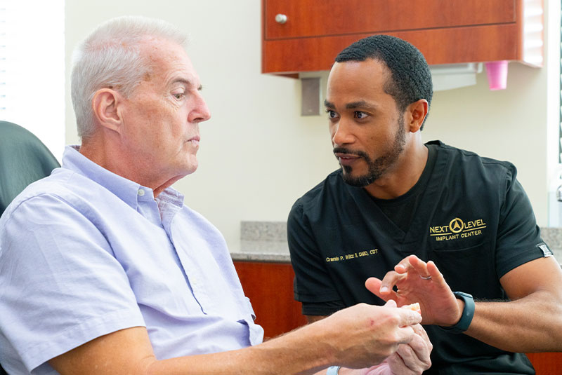 Dr Wiltz holding up model of implants for patient